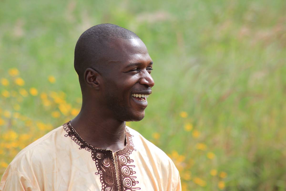 Nigerian man smiling in a field.